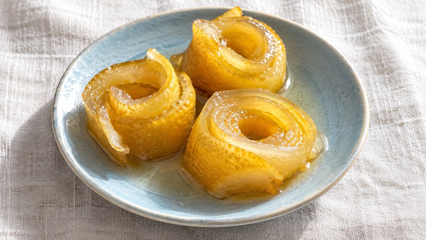 Bergamot kabuğu reçelini temsil eden tabakta üç altın sarısı kabuk rulosu